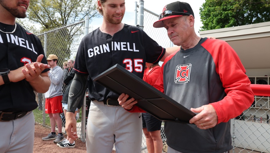 Two baseball players preset the head coach with an award for having 500 career wins.