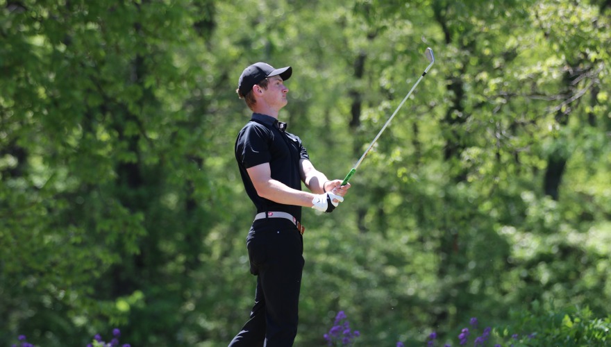 A men’s golfer looks on as he completes his drive.