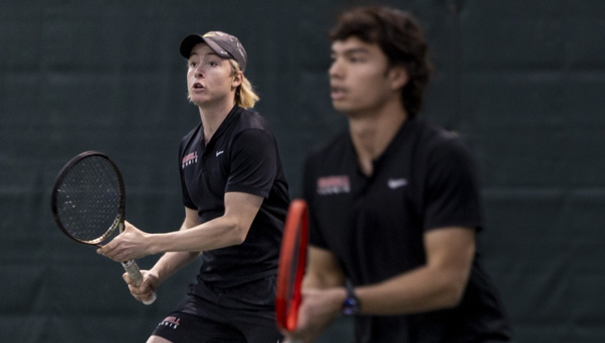 Two men’s tennis players watching their opponent from across the net.