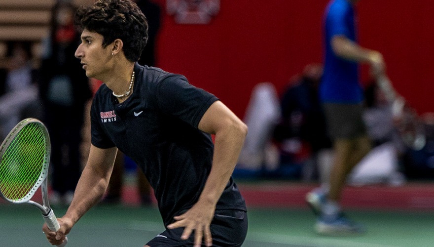 Men's tennis player in the ready position during an indoor match.