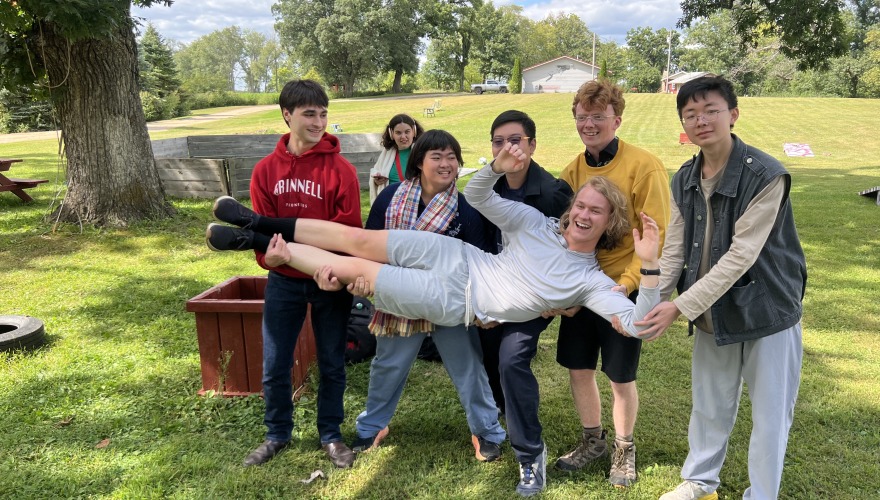 Small group of Singers holding a student in the air, all are laughing.