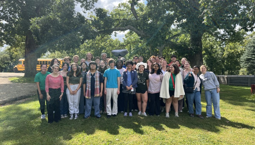 Group photo of Grinnell Singers standing by their bus on tour!