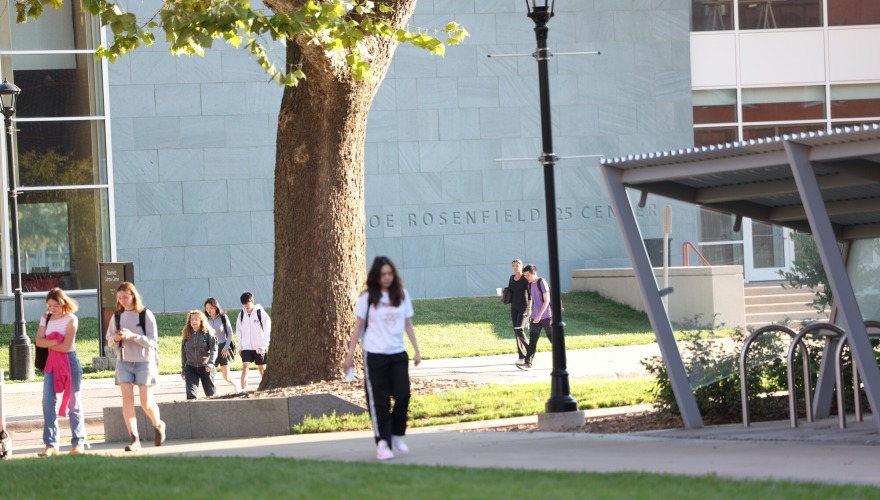Students walk across 8th Avenue in front of the bike racks.