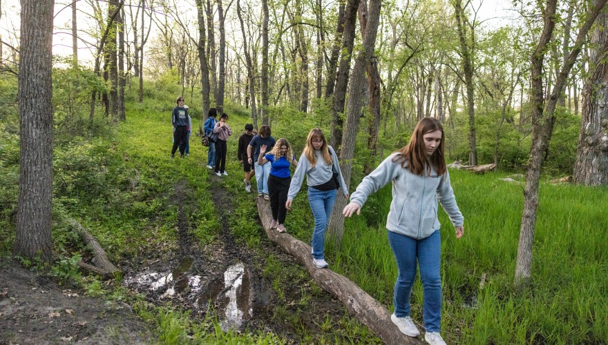 students walking across a log outdoors