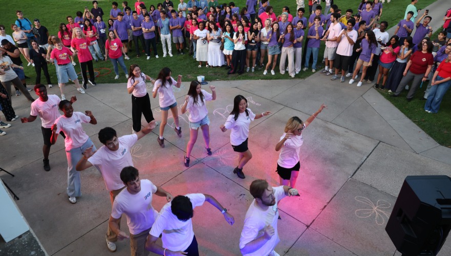 Students in pre-orientation programs form a circle around a group of students dancing at the All Pop event.