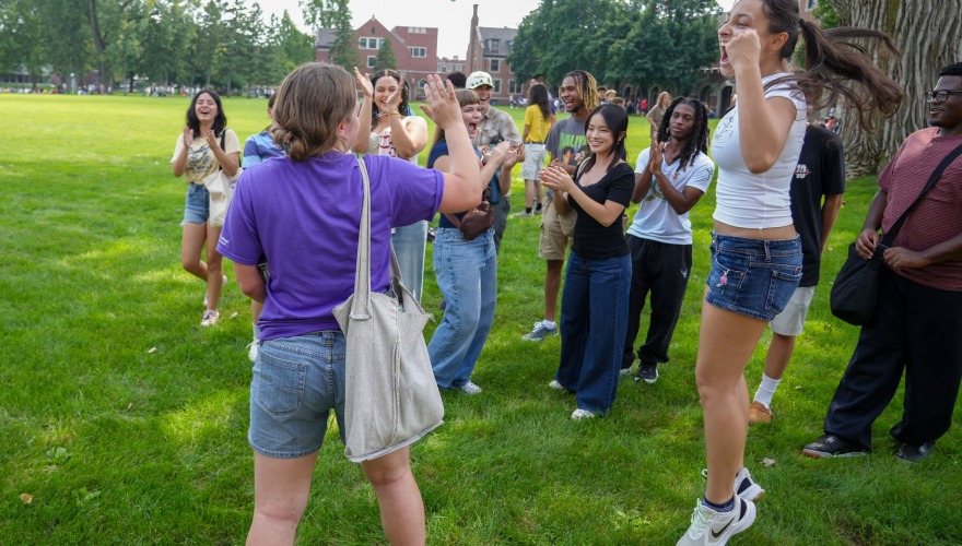 A small group of students and their mentor celebrate winning a game of rock, paper, scissors.