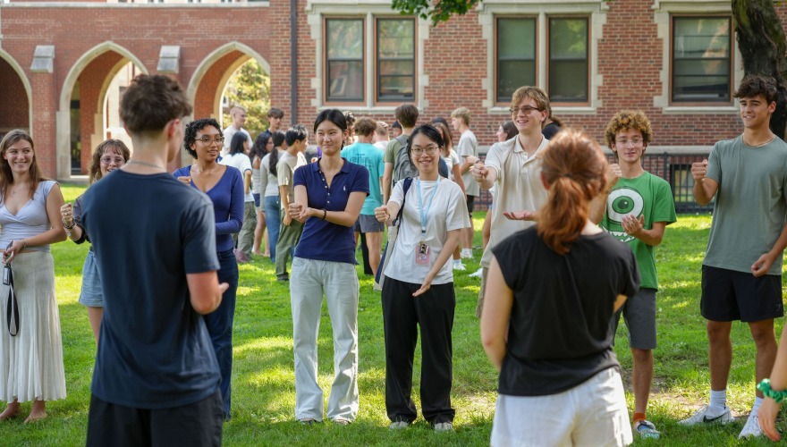 A group of new students face each other in a line on Mac Field.