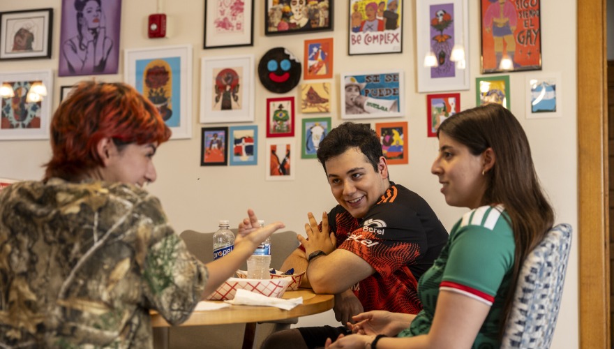 Students sit at table and enjoy conversation while eating