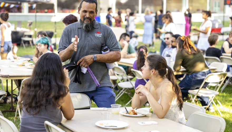 Three people talking outside at table