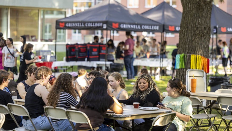 Students sit at table outside and enjoy food