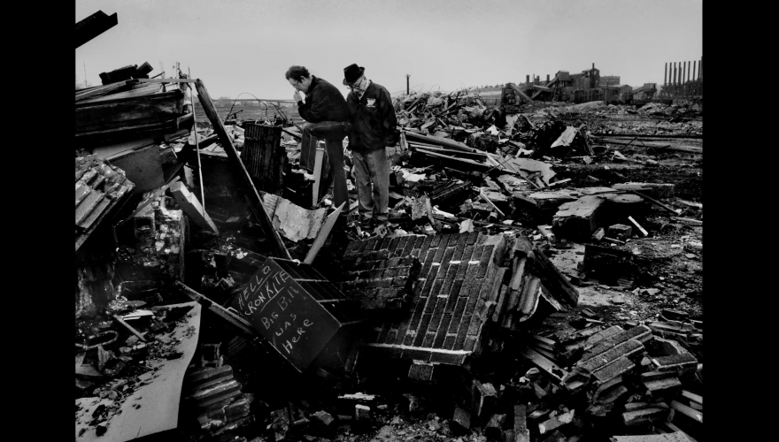 Two men viewing desctruction of buildings that have been flattened