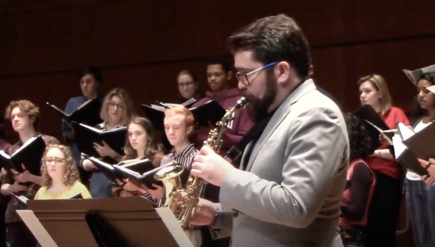 Professor Mark Laver playing saxophone with the Grinnell Singers