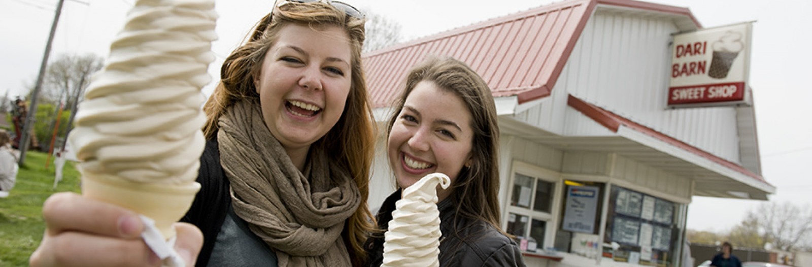 Two smiling customers hold Dari Barn ice cream cones.