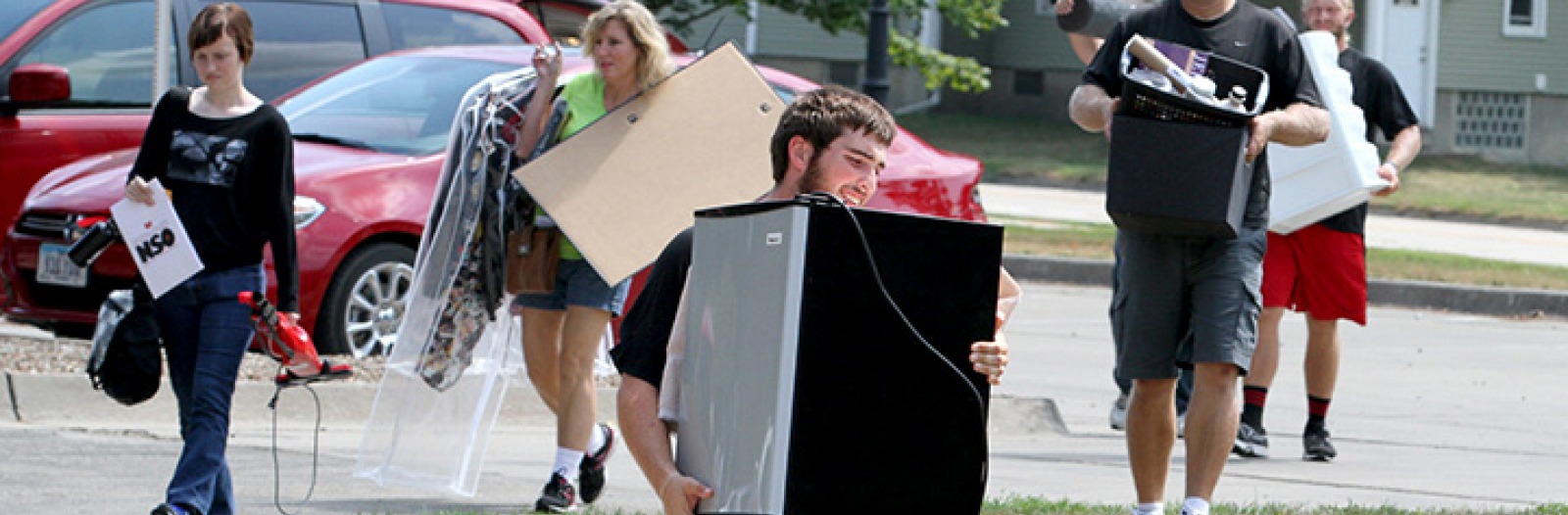 Family members help students carry belongings to a residence hall.