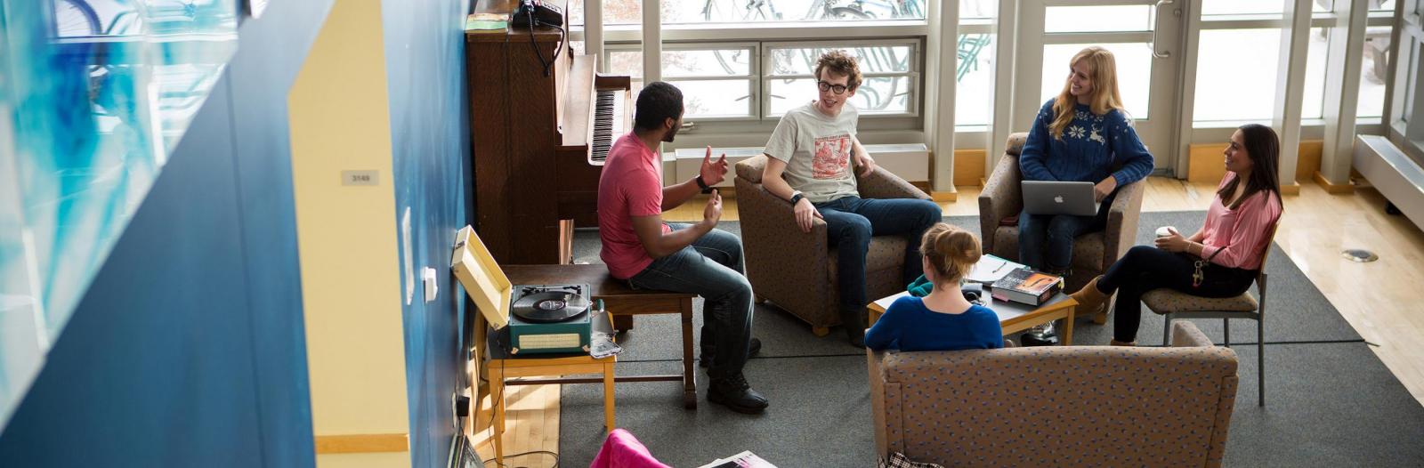 Students sit in chairs in an East Campus dorm foyer