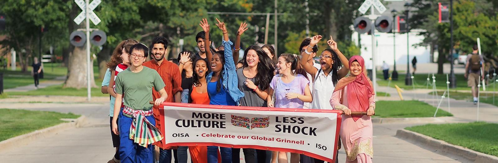 diverse students holding banner that says more culture, less shock, celebrate our global Grinnell, OISA, ISO 