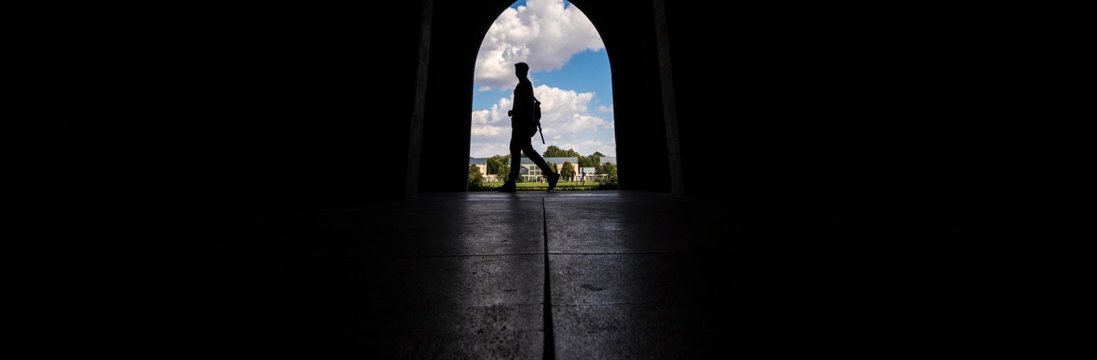 Silhouette of student walking in loggia archway