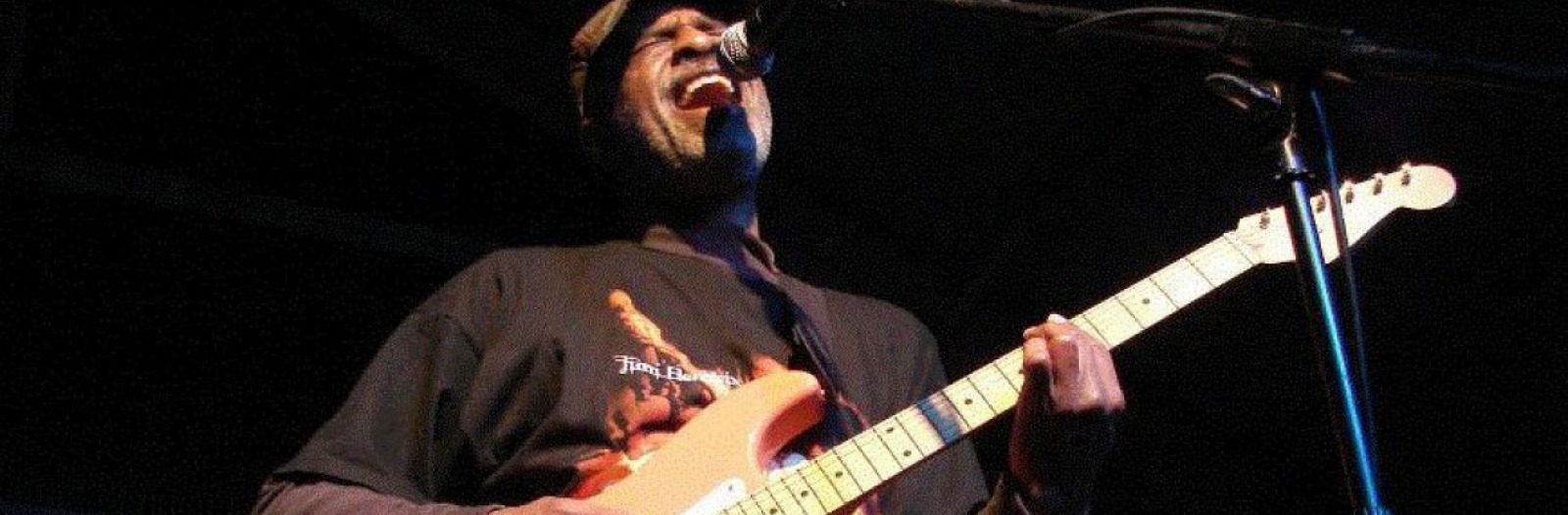 Dartanyan Brown plays bass guitar and sings into a microphone