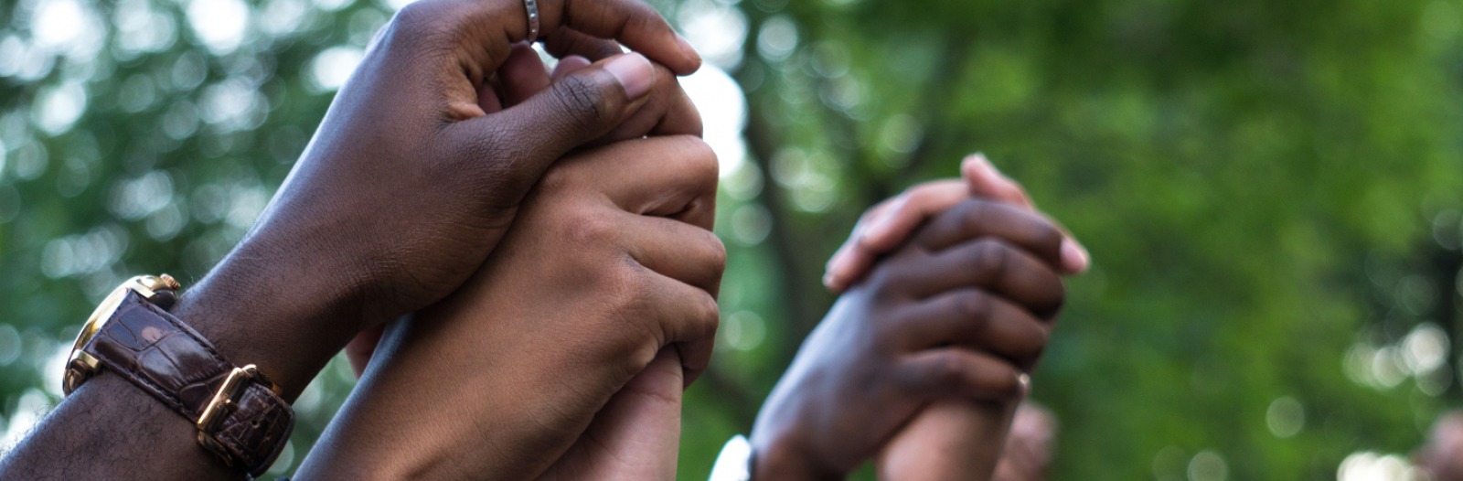 Close-up of Black people's raised, clasped hands