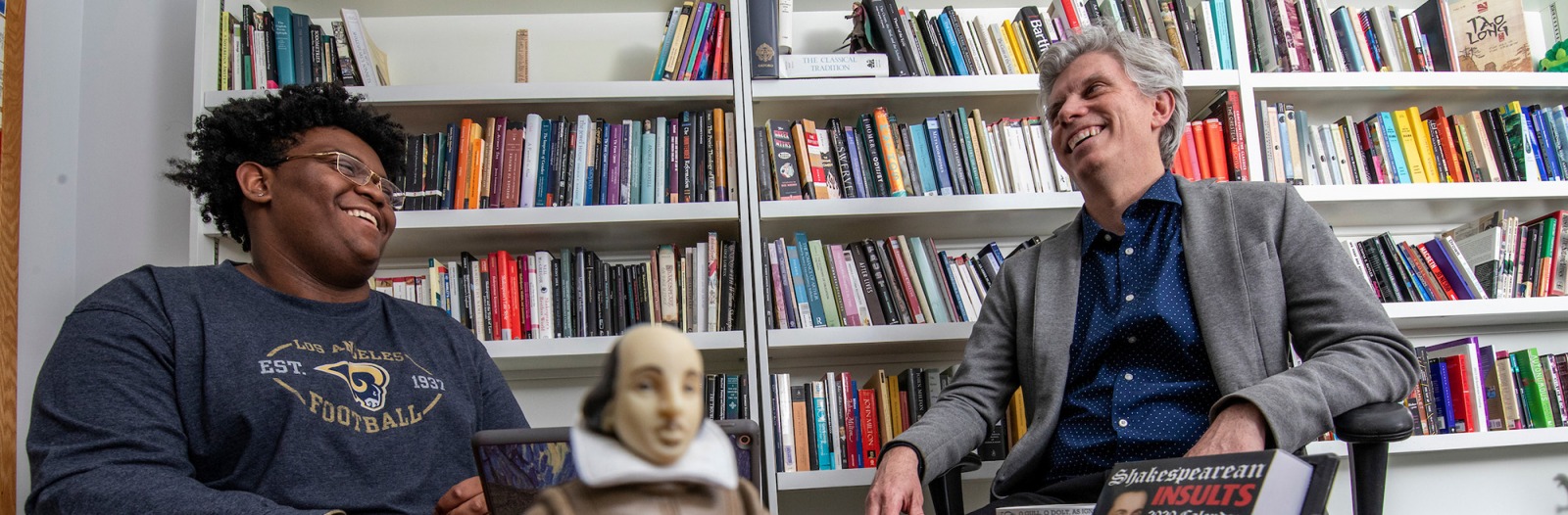 Professor Garrison and student in office with toy Shakespeare figure in foreground