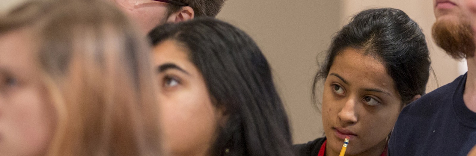 Close-up of a student's face as she stands among other students, all looking intent
