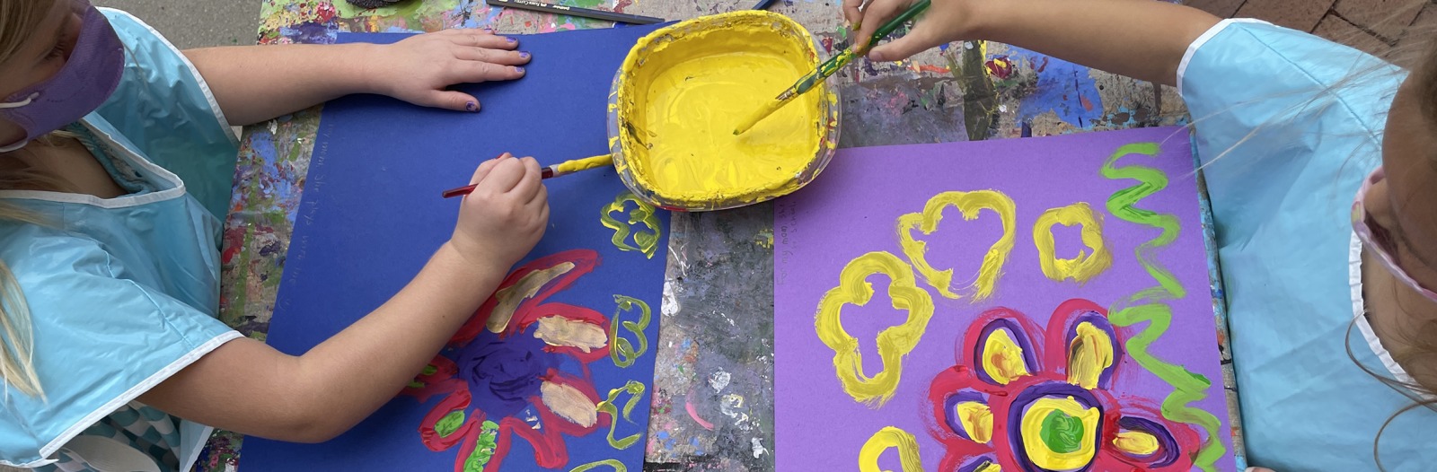 Overhead view of two children painting flowers