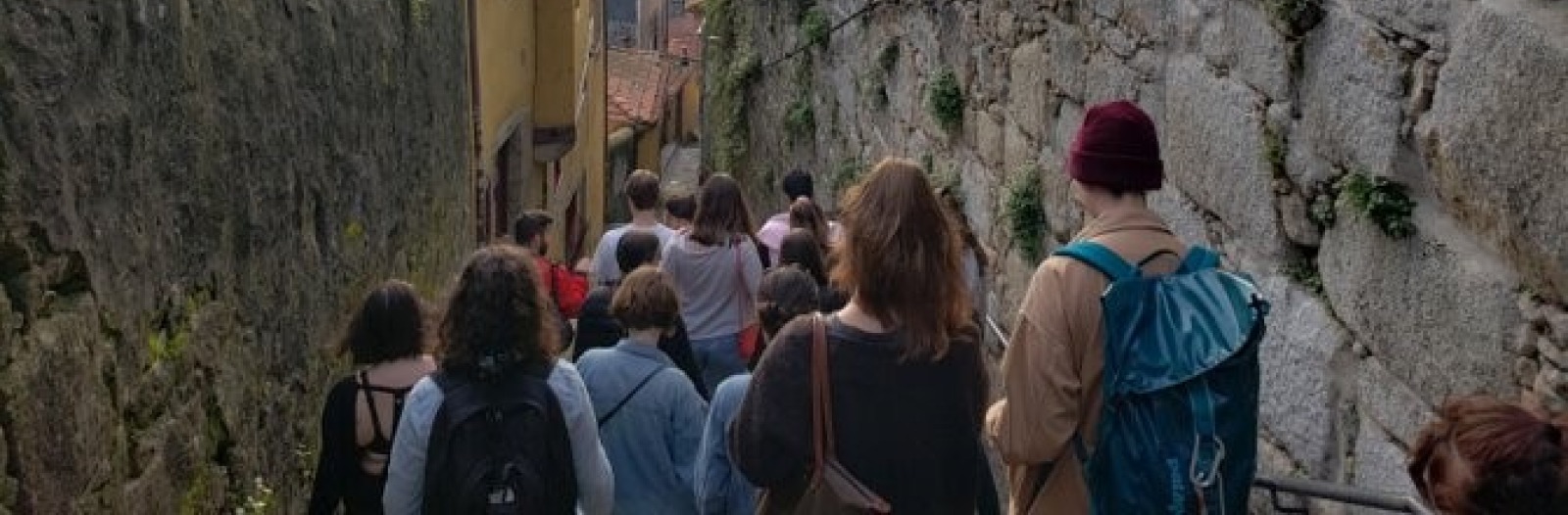 Group of student walking down a stone-wall lined ramp towards old buildings