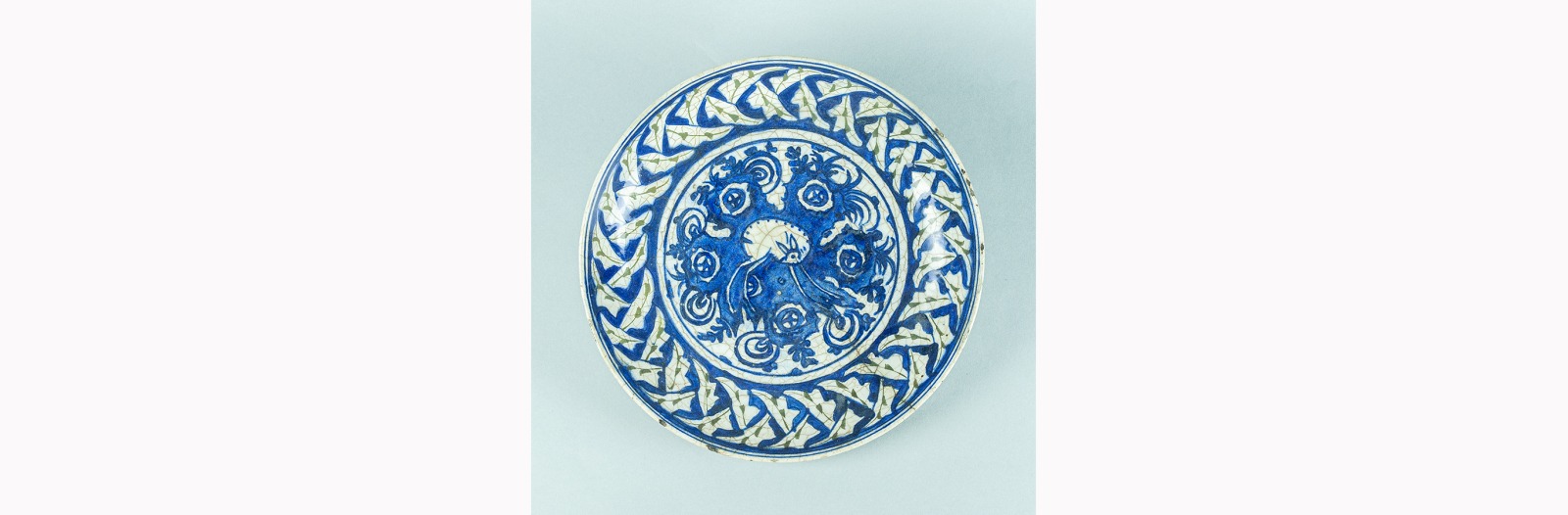 Image of a patterned blue and white dish with a stylized small deer-like animal at the center.