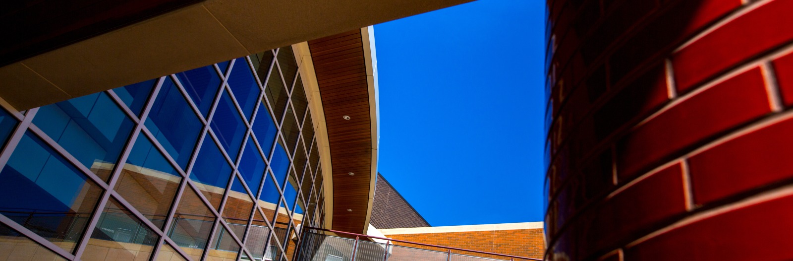 An abstract angle of the Joe Rosenfield Center. On the left, a glass, gridded wall and on the right, a close up of a red bricked pillar.