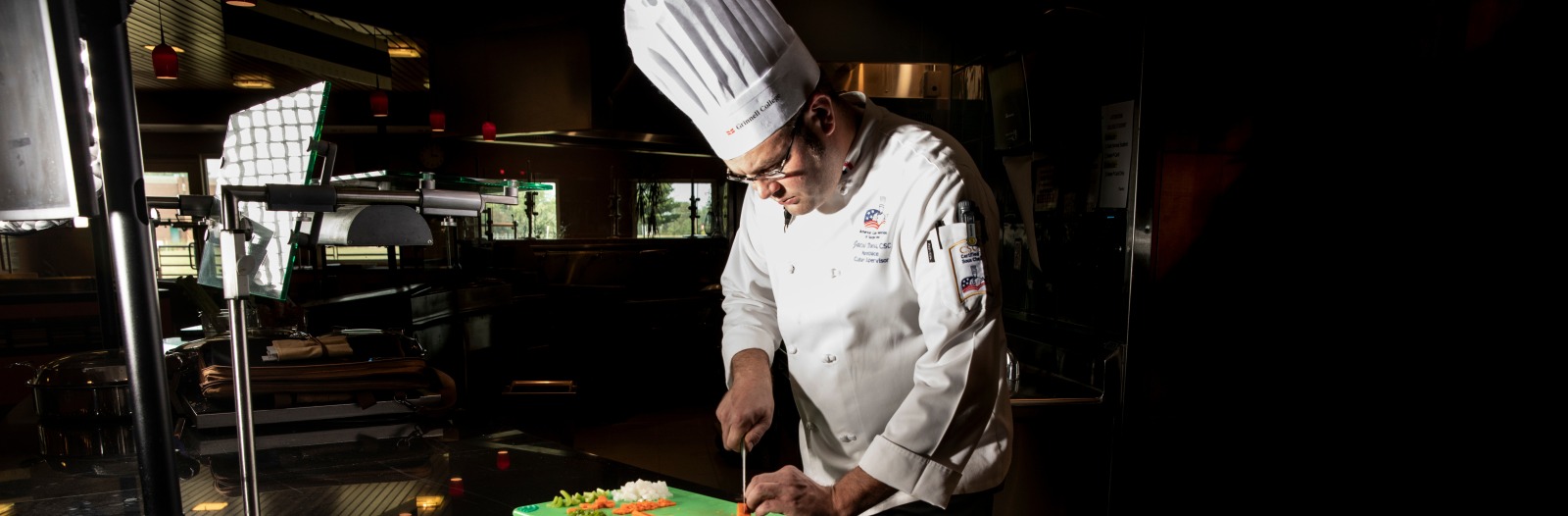 Man in chef's attire cutting food 