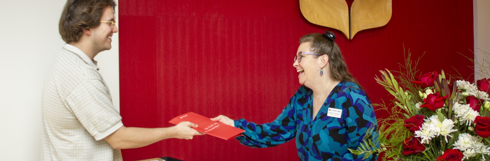 a student receives a folder from a receptionist