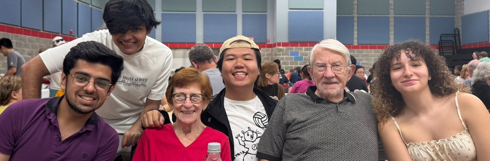 A group of people sit in a row at a table and smile at the viewer