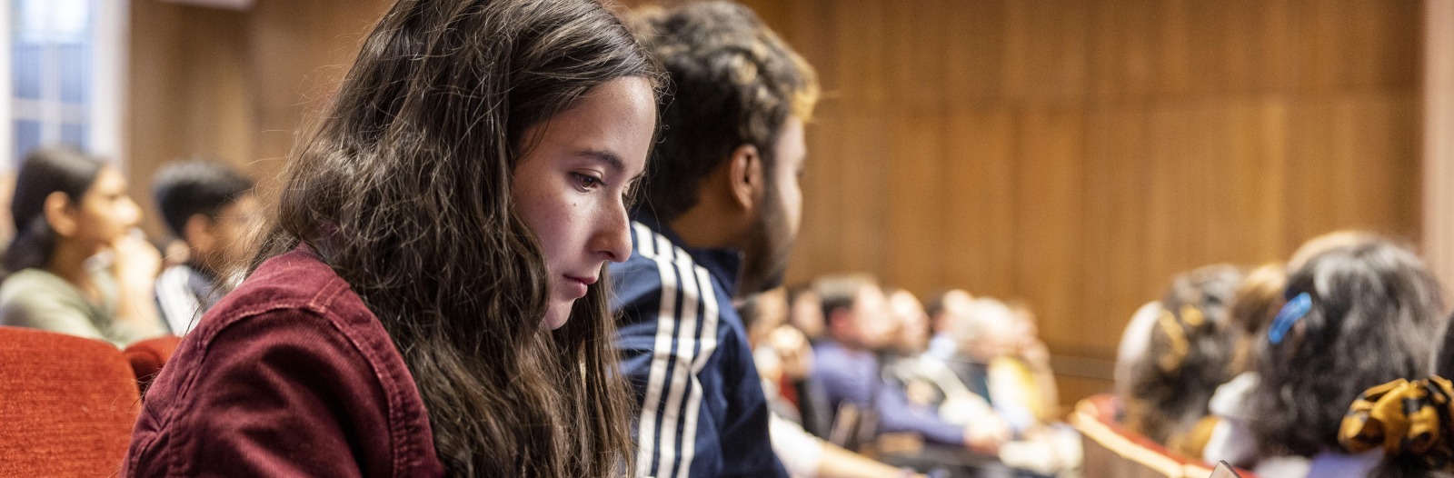 A student in a lecture hall takes notes on her laptop.