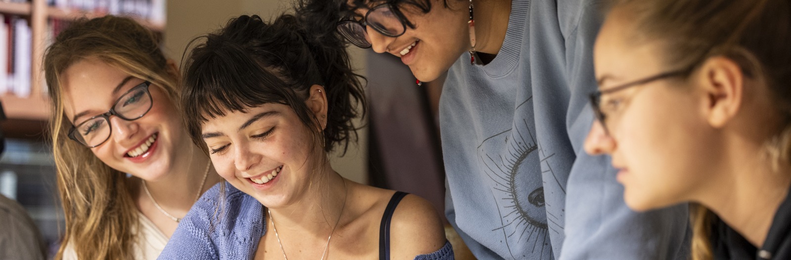 Four Grinnell College art history students at a table examining artwork in the Iowa Room of the Drake Community Library in Grinnell. 