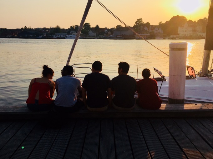 Group of students sitting on dock watching sunset