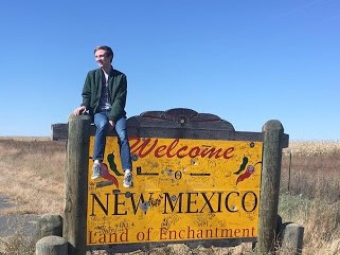 Student sitting on New Mexico sign 