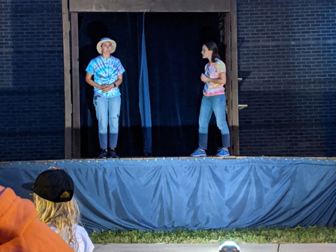 Two actors on stage in jeans and tie-dye tshirts
