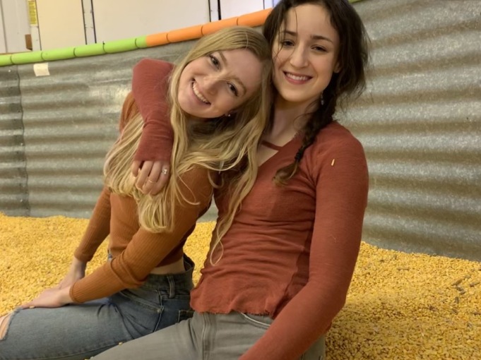 two women sitting in a pile of corn