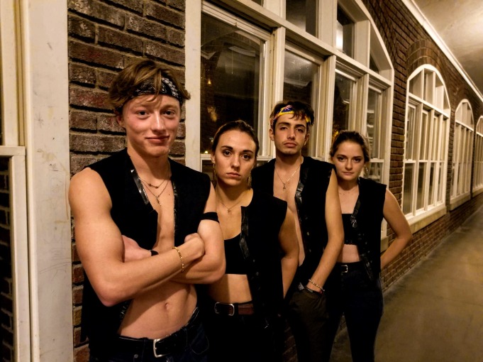 Me and my friends in matching biker vests and bandanas around our foreheads leaning against bricks and windows in South loggia