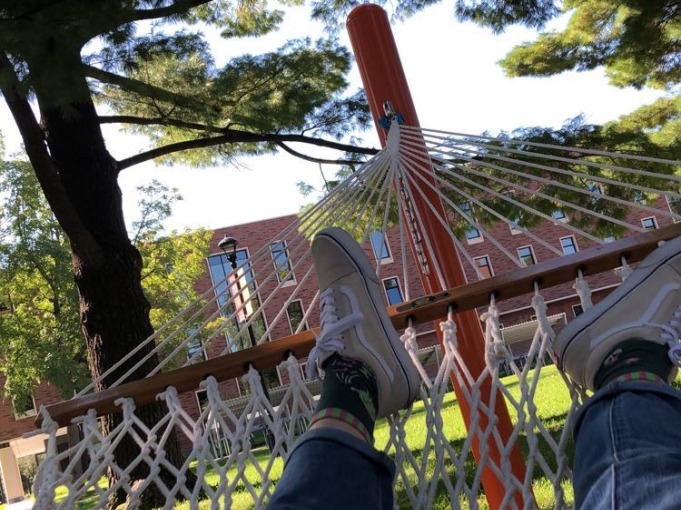 Picture of me sitting in the hammocks outside of Younker Hall. You can see my foot and the Humanities and Social Sciences Center in between two trees.
