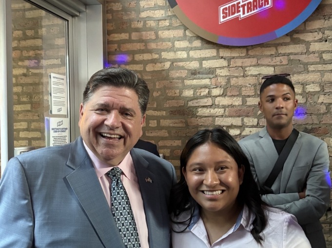 Maria and a man in a suit excitedly take a picture together.