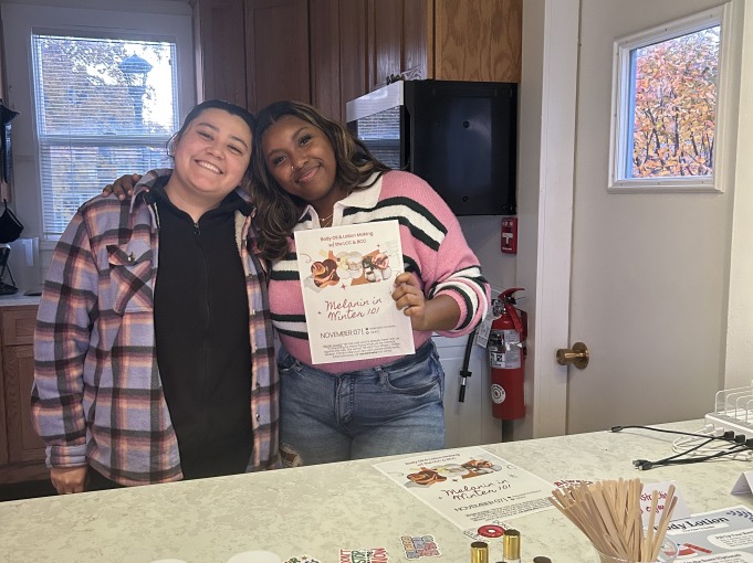 A fellow student and I smile and hold up a flyer for BCC x LCC collaborative "Melanin in Winter" event.