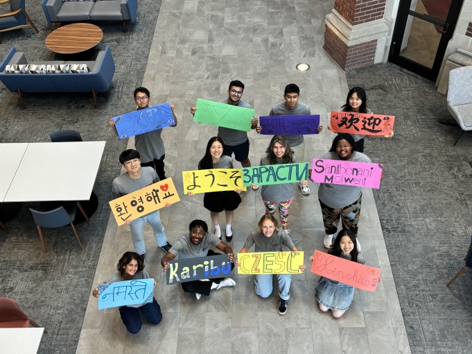 Student mentors from International Pre-Orientation Program hold up signs in their native language that welcome international students.