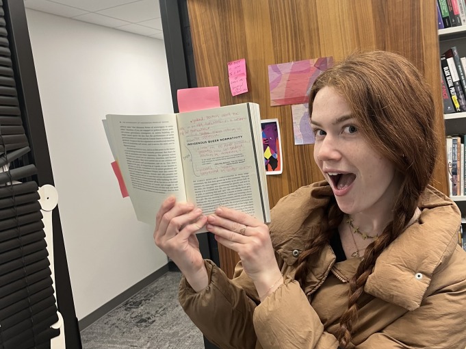 Sage excitedly holds a book next to her face.