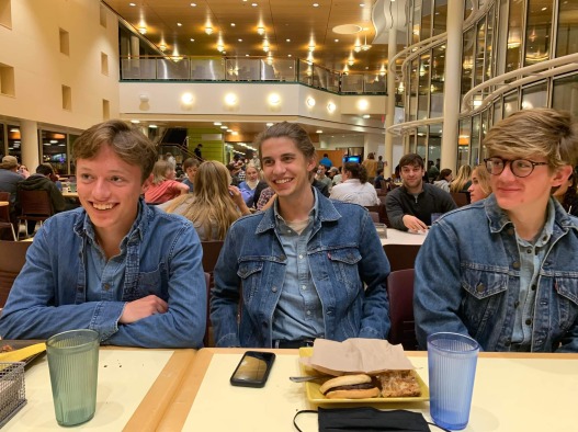 Me and my friends sitting in matching denim vests together at a dining hall table
