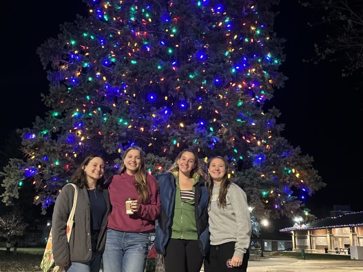 My friends and I gather under a Christmas tree.