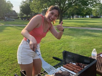 Girl posing for picture in front of grill