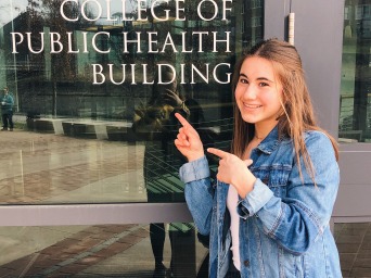 Student pointing at college health building door sign