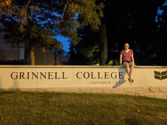 Ailsa sitting on stone entrance sign for Grinnell College
