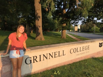 Enya Gamble in front of Grinnell College entrance sign